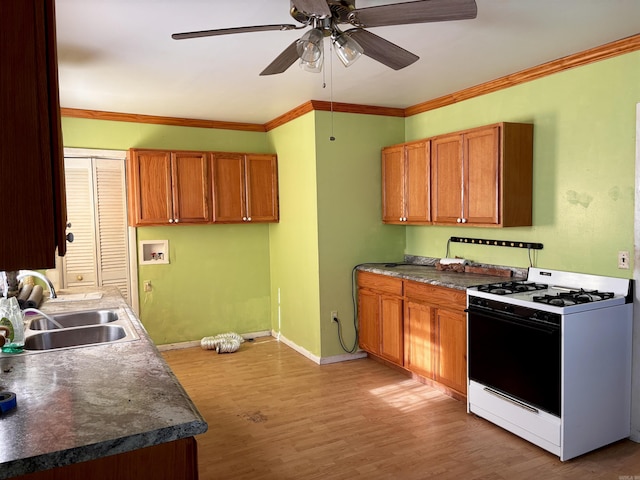 kitchen featuring light wood finished floors, brown cabinets, a sink, and gas stove