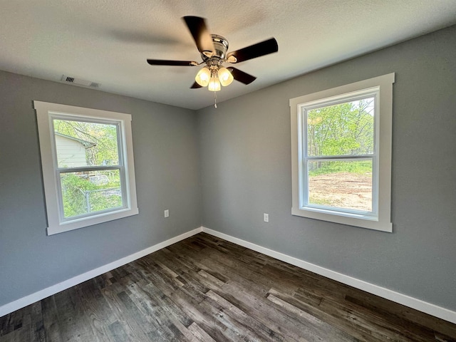 spare room with baseboards, plenty of natural light, and dark wood-style floors