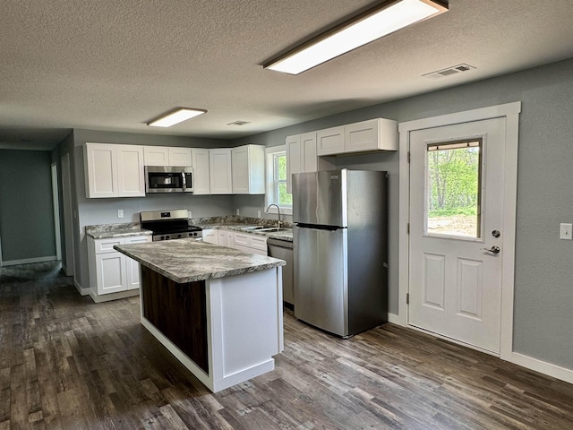 kitchen featuring visible vents, a sink, appliances with stainless steel finishes, a textured ceiling, and white cabinetry
