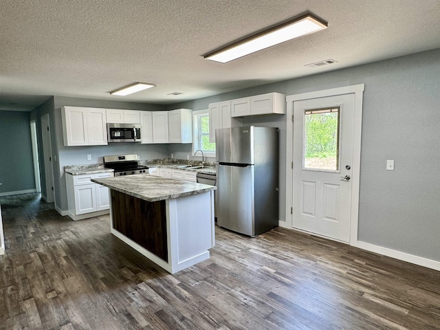 kitchen featuring a textured ceiling, white cabinetry, visible vents, appliances with stainless steel finishes, and a sink