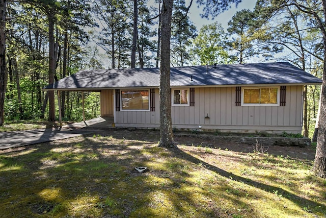 exterior space featuring an attached carport, board and batten siding, a shingled roof, and driveway