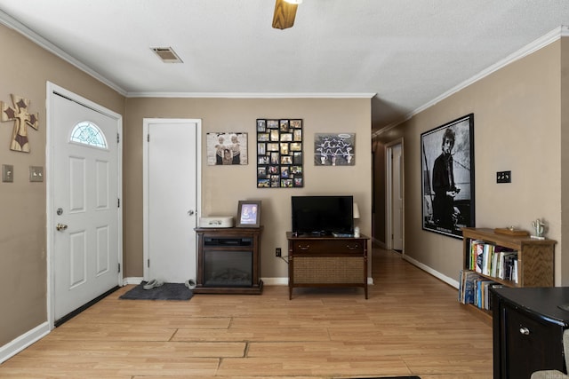 entryway featuring baseboards, visible vents, light wood-style floors, and ornamental molding