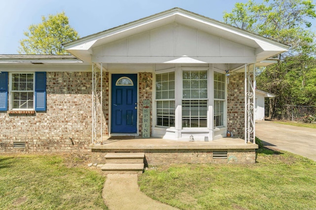 view of front of house with crawl space, covered porch, brick siding, and a front yard