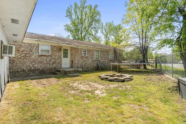 back of property with a yard, a trampoline, crawl space, and a fenced backyard