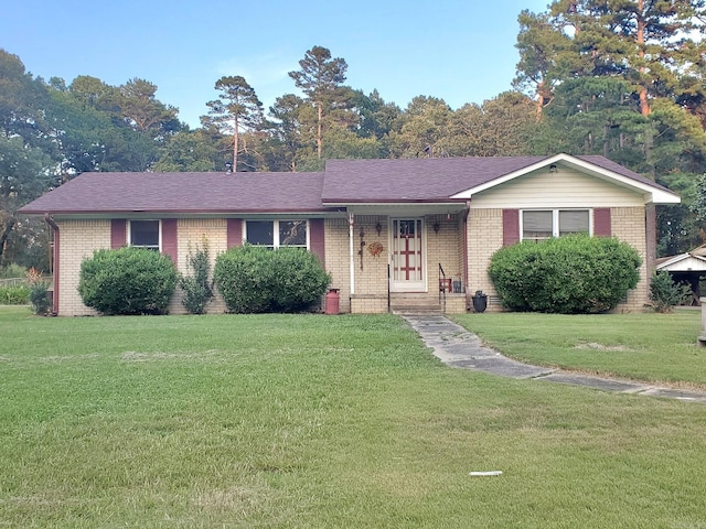 ranch-style house featuring a shingled roof, brick siding, and a front yard