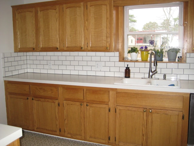 kitchen featuring backsplash, brown cabinets, a sink, and light countertops