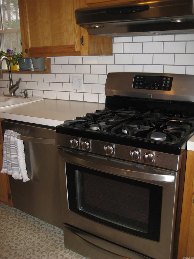 details with stainless steel appliances, a sink, backsplash, light countertops, and under cabinet range hood