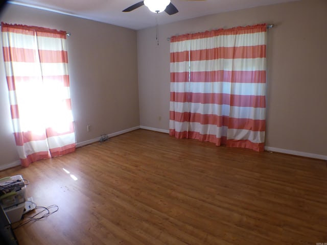 unfurnished room featuring baseboards, wood finished floors, and ceiling fan