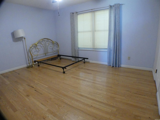 unfurnished room with wood finished floors, baseboards, and ceiling fan