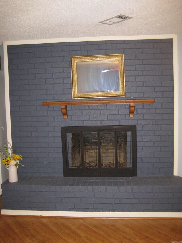 interior details with baseboards, wood finished floors, visible vents, and a fireplace