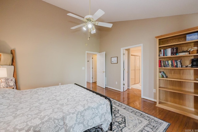 bedroom featuring ceiling fan, baseboards, wood finished floors, and a high ceiling