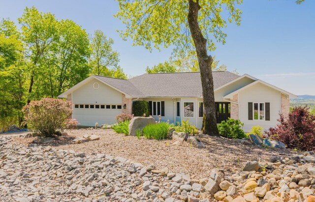ranch-style house featuring an attached garage and roof with shingles