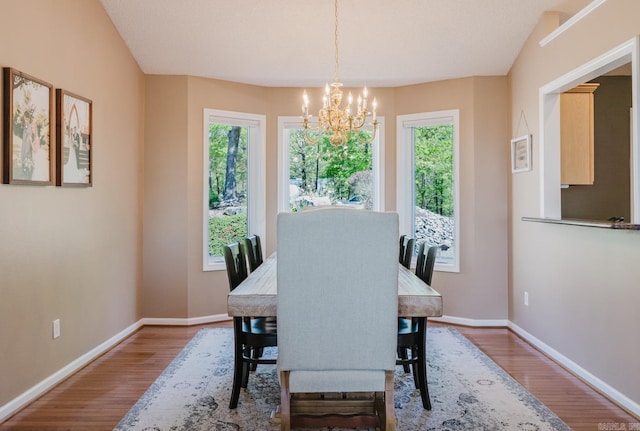 dining space with plenty of natural light, wood finished floors, and an inviting chandelier