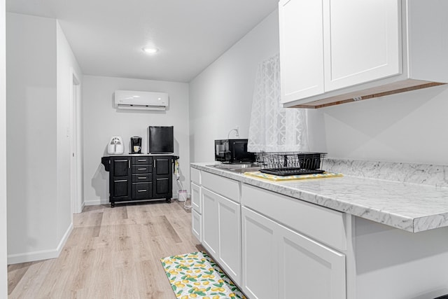 kitchen with a wall unit AC, light wood-type flooring, recessed lighting, white cabinetry, and black microwave