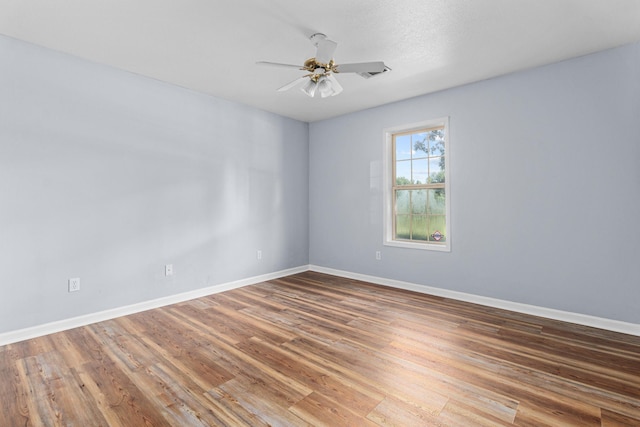 unfurnished room featuring baseboards, wood finished floors, and ceiling fan