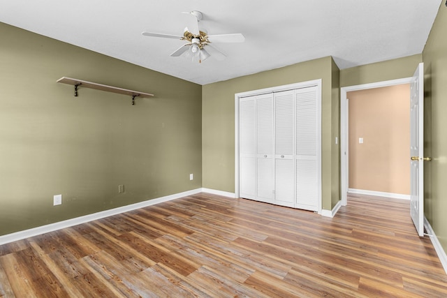 unfurnished bedroom with baseboards, a ceiling fan, wood finished floors, and a closet