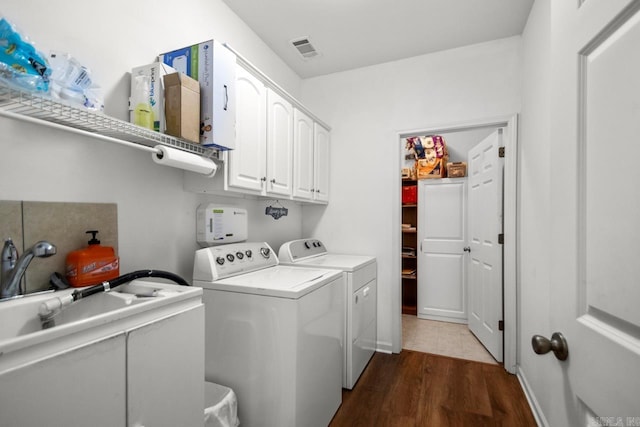 washroom featuring cabinet space, visible vents, dark wood-style floors, and separate washer and dryer
