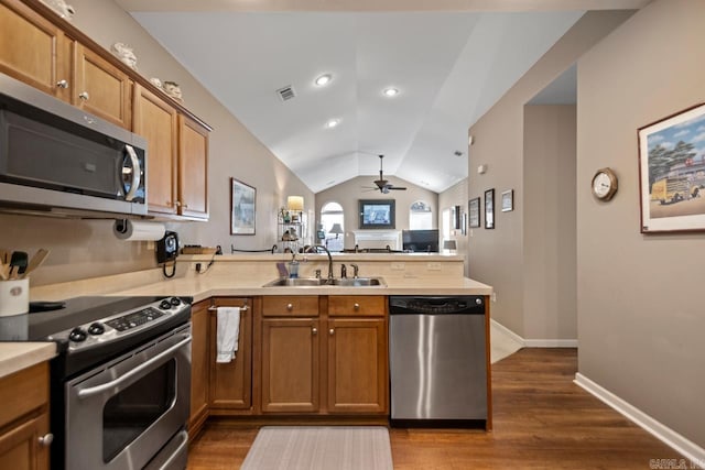 kitchen featuring a sink, stainless steel appliances, a peninsula, lofted ceiling, and visible vents