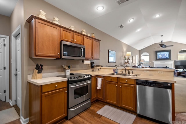 kitchen featuring a sink, a peninsula, appliances with stainless steel finishes, open floor plan, and ceiling fan