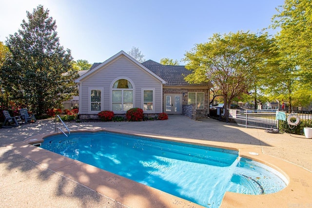 view of swimming pool with french doors, a patio area, a fenced in pool, and fence