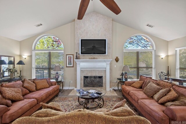 living area with a tiled fireplace, visible vents, baseboards, and ceiling fan