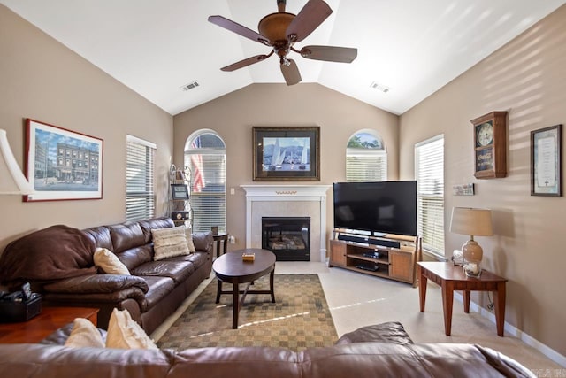 living area with a tiled fireplace, lofted ceiling, visible vents, and ceiling fan