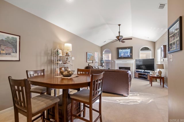 dining room featuring a fireplace, lofted ceiling, a wealth of natural light, and a ceiling fan