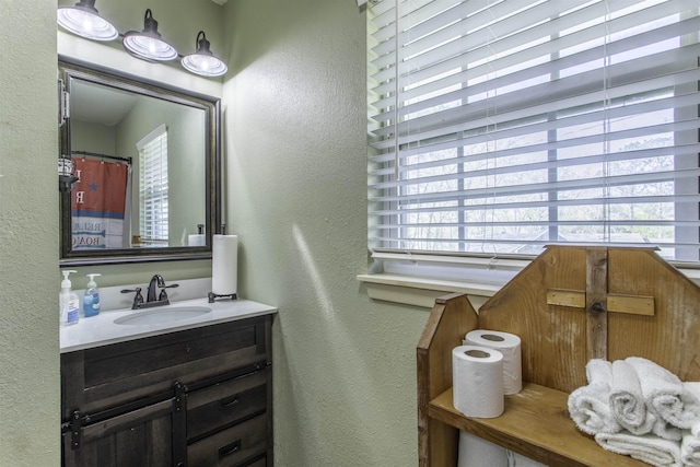 bathroom with a textured wall and vanity