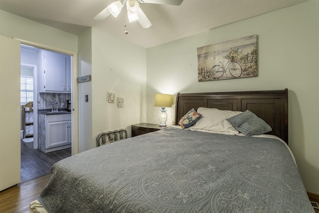 bedroom with ceiling fan, wood finished floors, and a sink