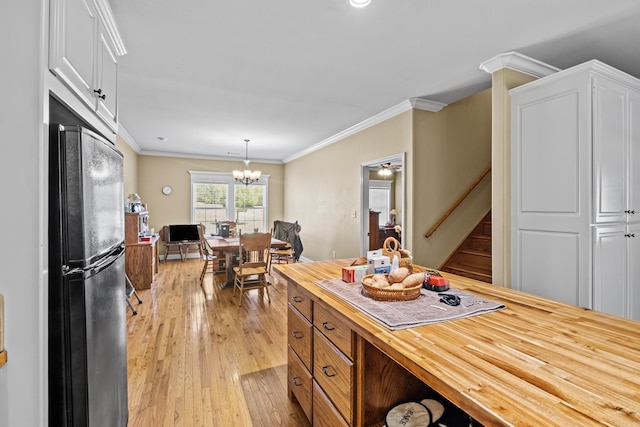 kitchen with light wood-style flooring, freestanding refrigerator, a notable chandelier, butcher block countertops, and white cabinetry