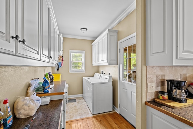 laundry area featuring crown molding, cabinet space, light wood-style flooring, washing machine and dryer, and baseboards