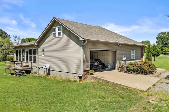 back of house featuring a yard, an attached garage, a wooden deck, driveway, and roof with shingles