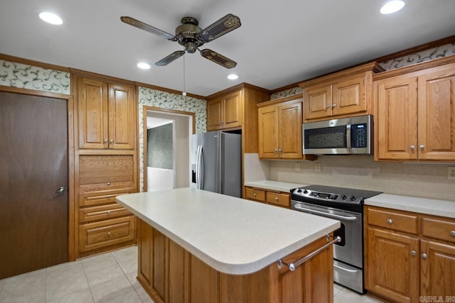 kitchen featuring ceiling fan, stainless steel appliances, a kitchen island, and light countertops