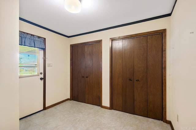 unfurnished bedroom featuring two closets, crown molding, and baseboards