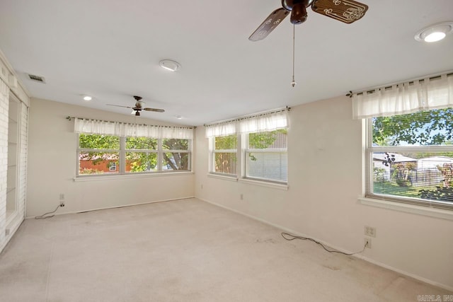spare room with carpet, a wealth of natural light, and ceiling fan