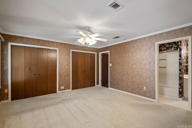 unfurnished bedroom with two closets, a ceiling fan, visible vents, and carpet
