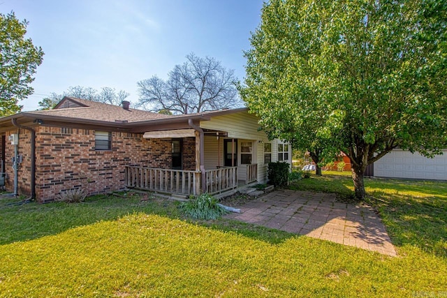 rear view of house featuring brick siding, a yard, and covered porch