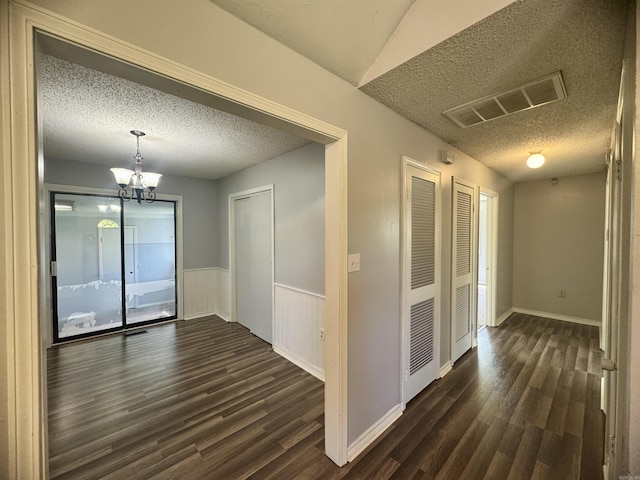 interior space with dark wood-type flooring, a textured ceiling, and visible vents
