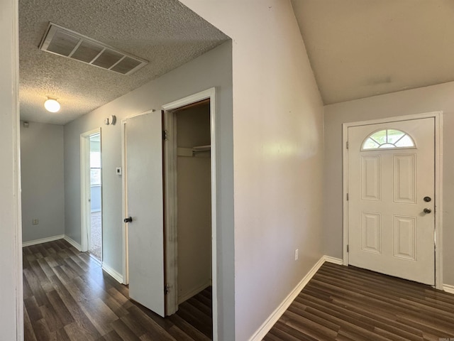 foyer entrance with visible vents, a textured ceiling, a healthy amount of sunlight, and dark wood-style flooring