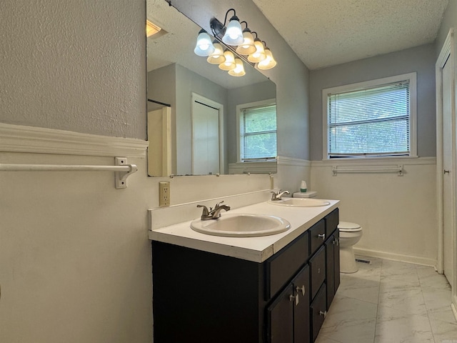 full bath featuring marble finish floor, a sink, double vanity, and toilet