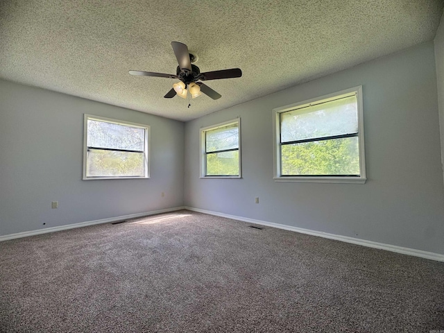 empty room featuring a textured ceiling, visible vents, baseboards, ceiling fan, and carpet floors