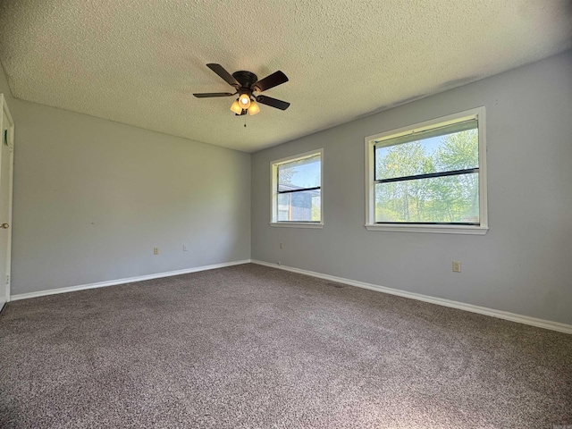 spare room with baseboards, a ceiling fan, dark colored carpet, and a textured ceiling
