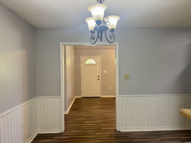 interior space with a wainscoted wall, wood finished floors, a textured ceiling, and a chandelier