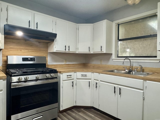 kitchen featuring a sink, stainless steel gas stove, white cabinets, under cabinet range hood, and dark wood-type flooring