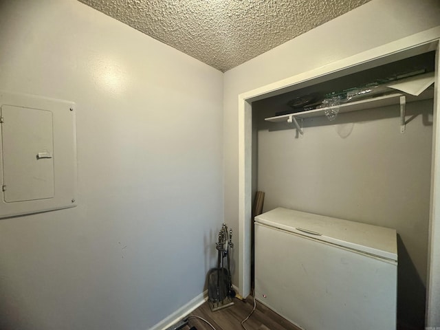laundry room featuring baseboards, dark wood-style flooring, a textured ceiling, and electric panel