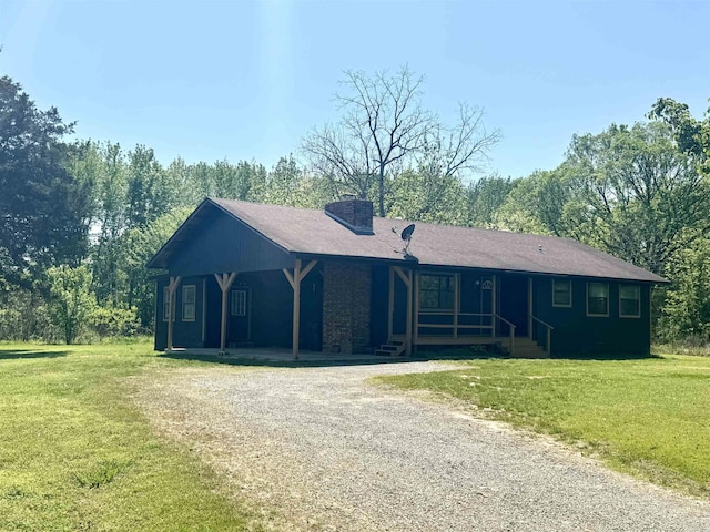 single story home with gravel driveway, a chimney, covered porch, and a front yard