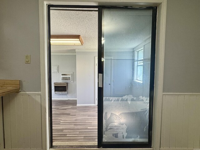 interior space featuring heating unit, wood finished floors, a textured ceiling, wainscoting, and wood walls