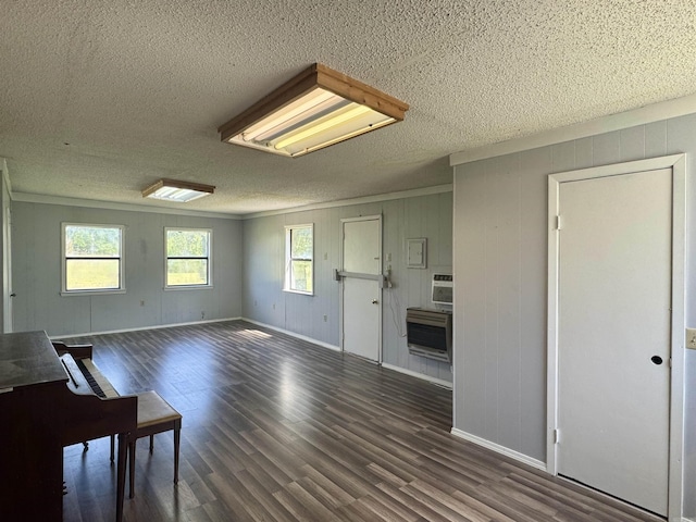 unfurnished living room featuring attic access, a textured ceiling, baseboards, heating unit, and wood finished floors