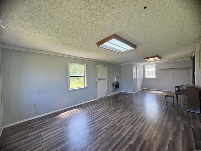 interior space with dark wood finished floors, baseboards, heating unit, and a textured ceiling