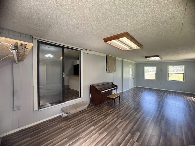 interior space with a decorative wall, wood finished floors, a textured ceiling, and baseboards